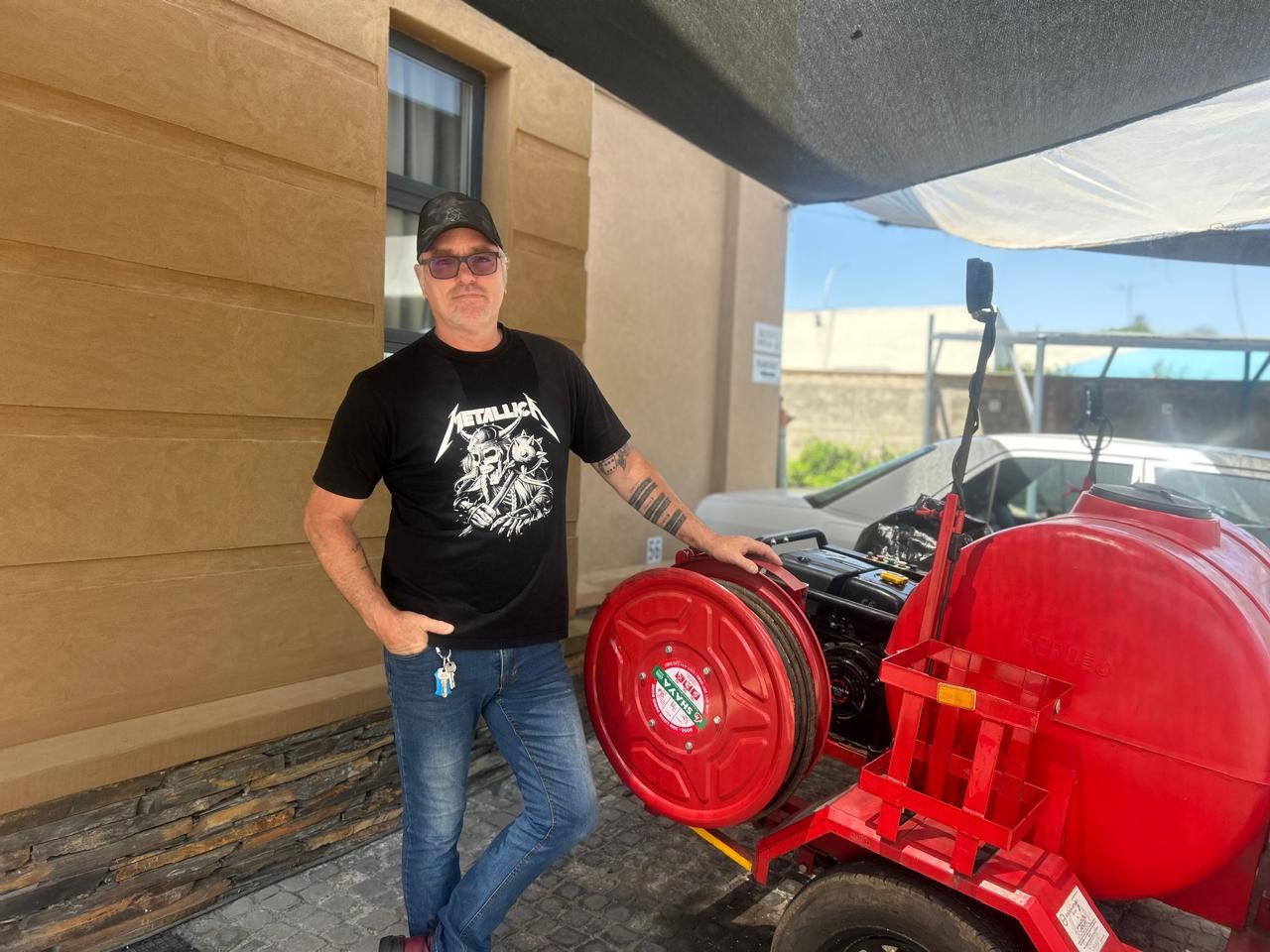 Antonio Tony Bekker beside the red drain-jetting trailer and hose reel
