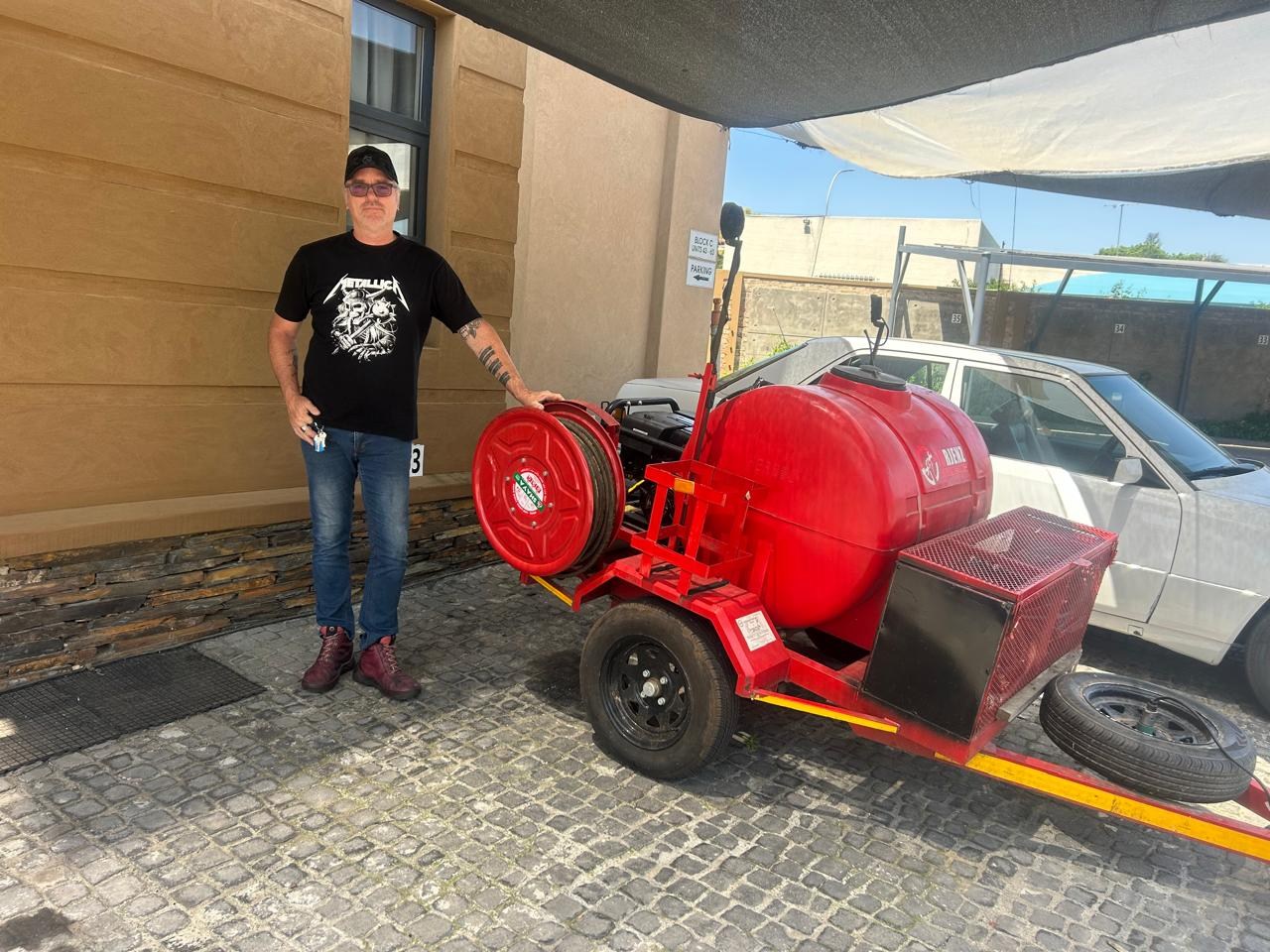 Tony beside the red jetting trailer, water tank and hose reel